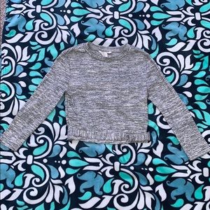 A light grey crop top that is long sleeve